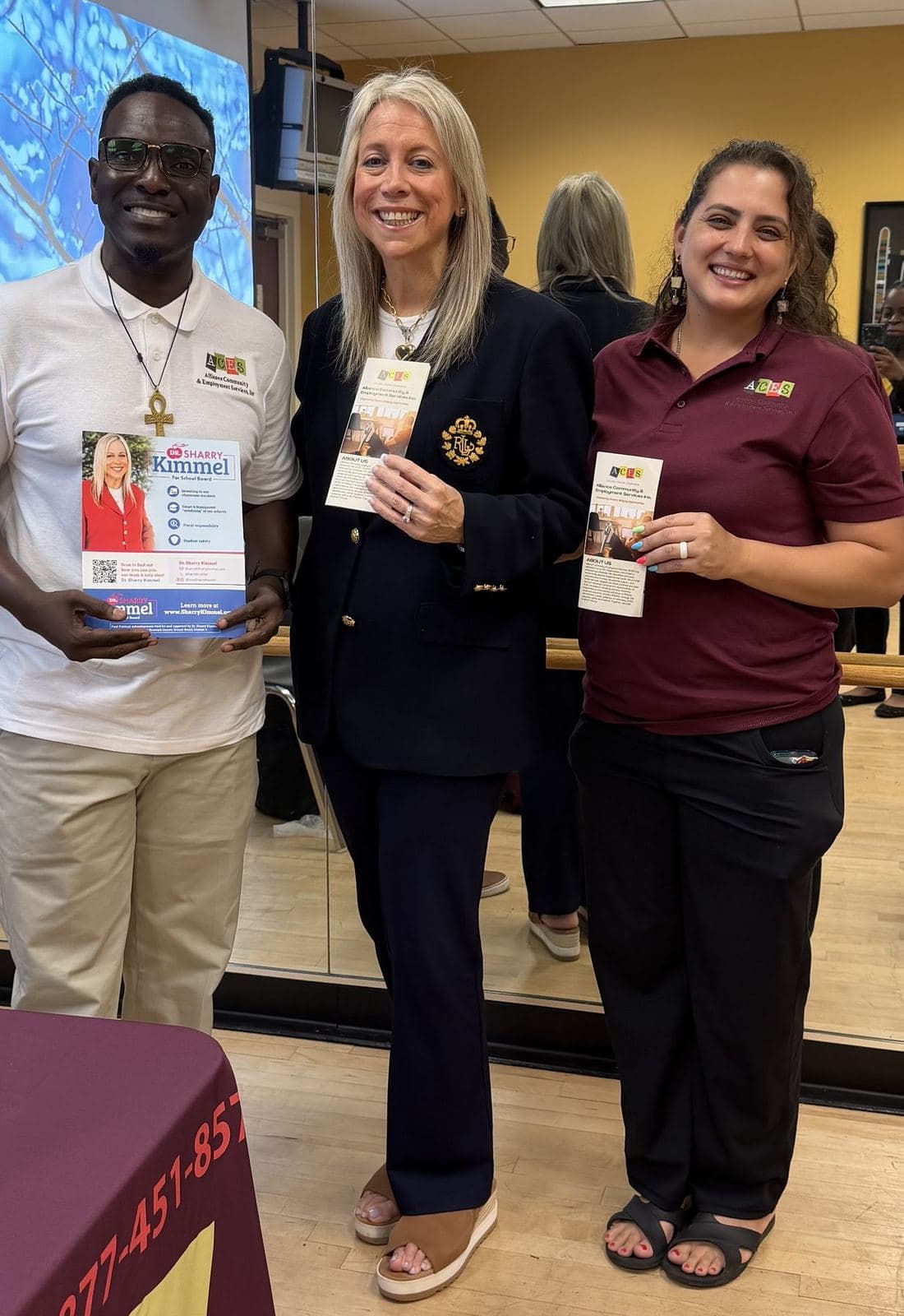 Three ACES team members and a community partner holding program flyers at an outreach event