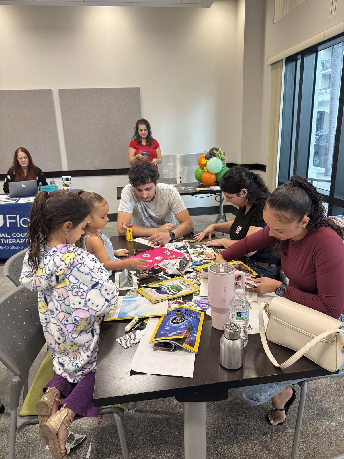 Families and children working together on a creative collage activity around a table at an ACES workshop