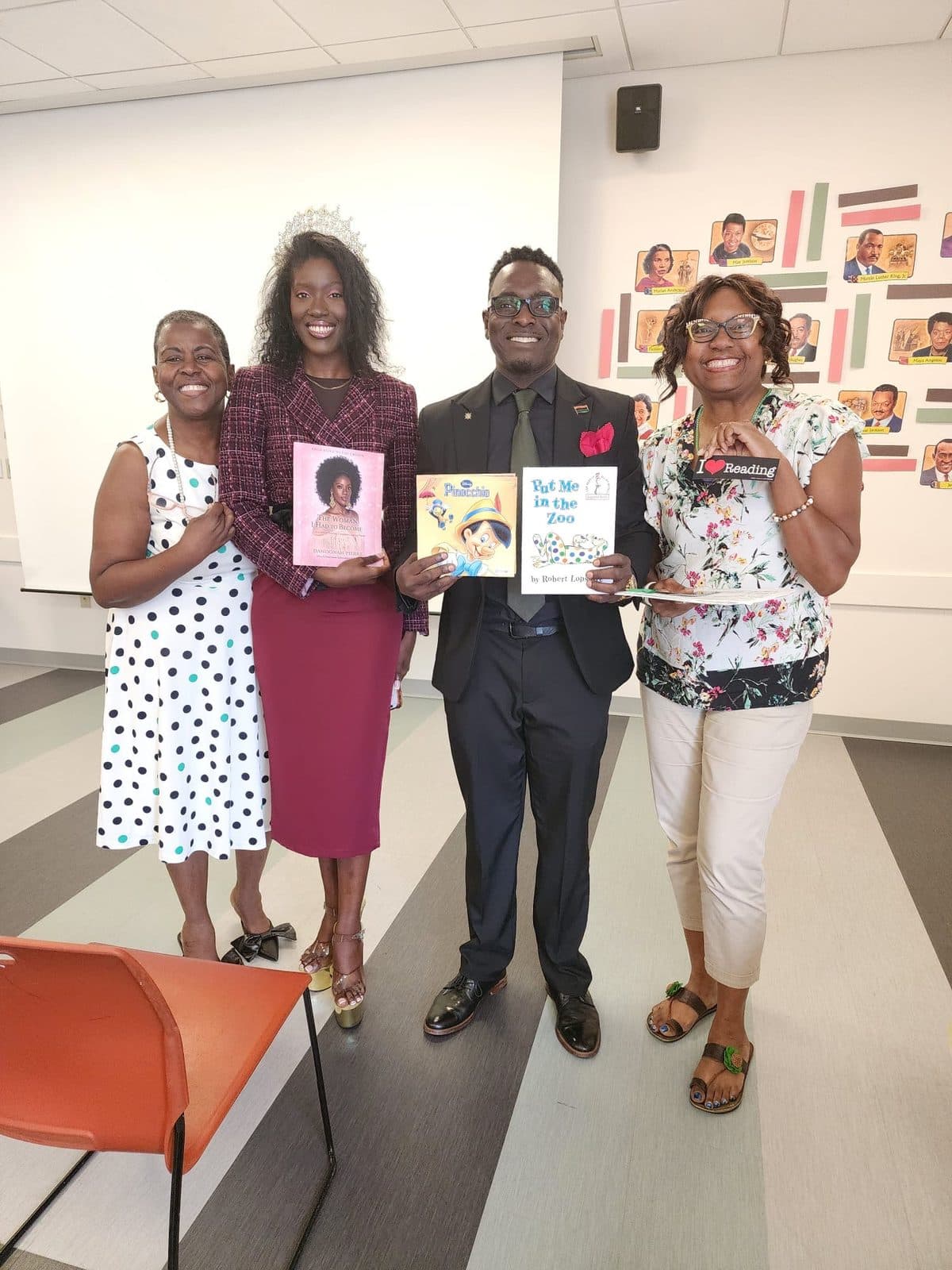 Four community members holding children's books at an ACES literacy and education event